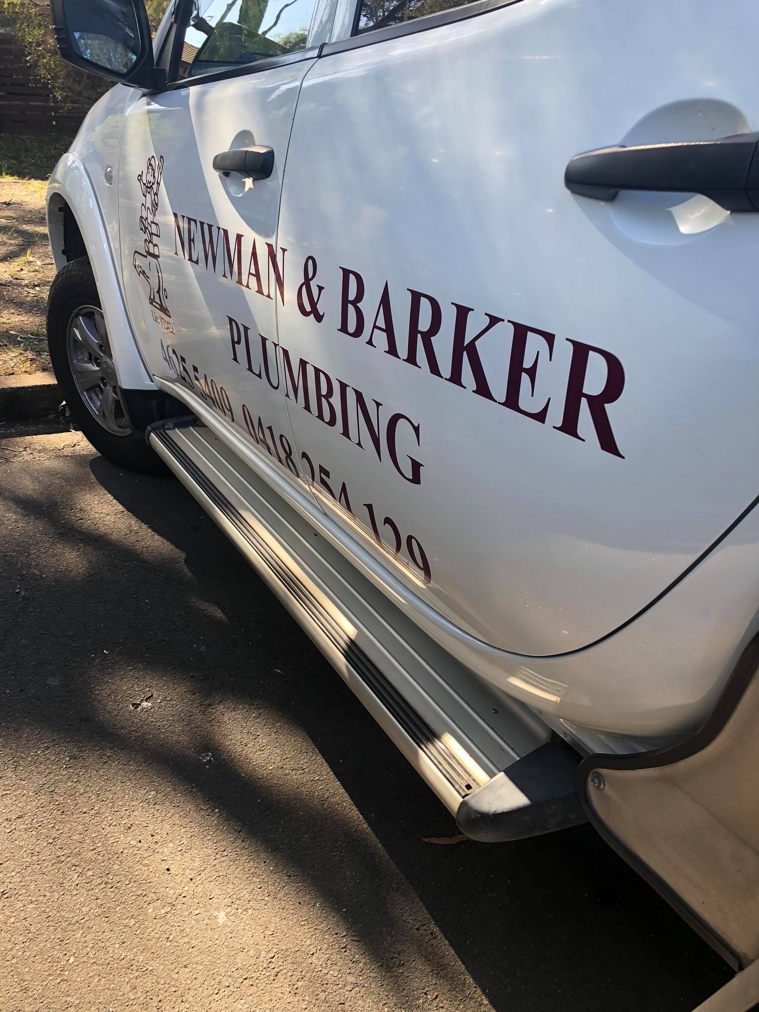 a car with a sign newman and barker plumbing on the left side
