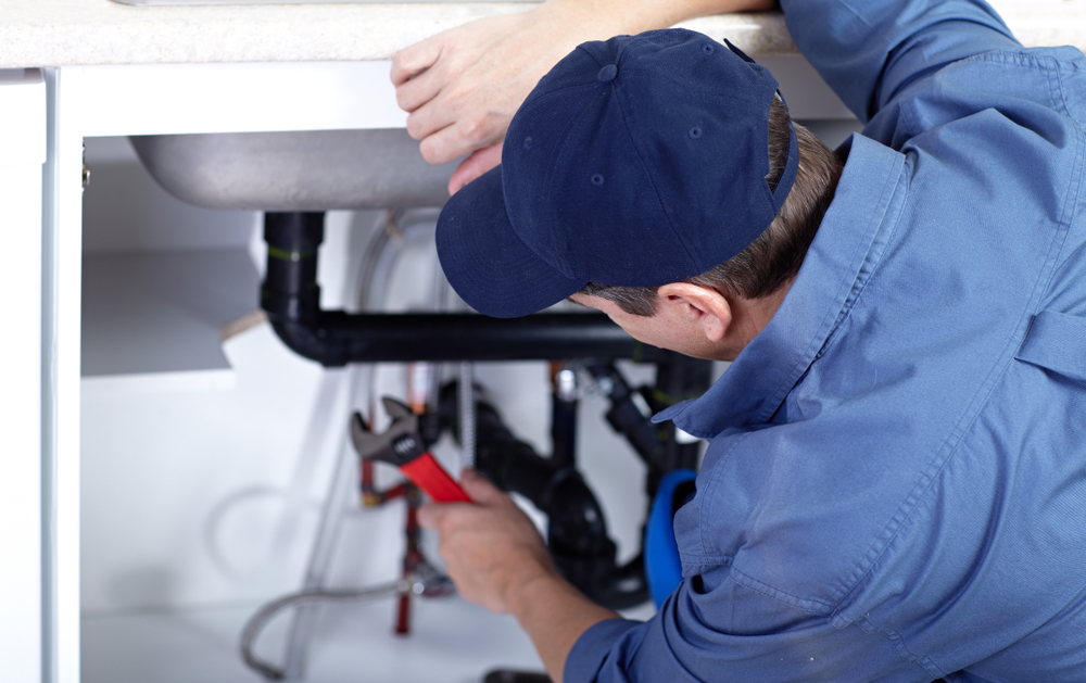 A photo of professional qualified plumber repairs a sink.